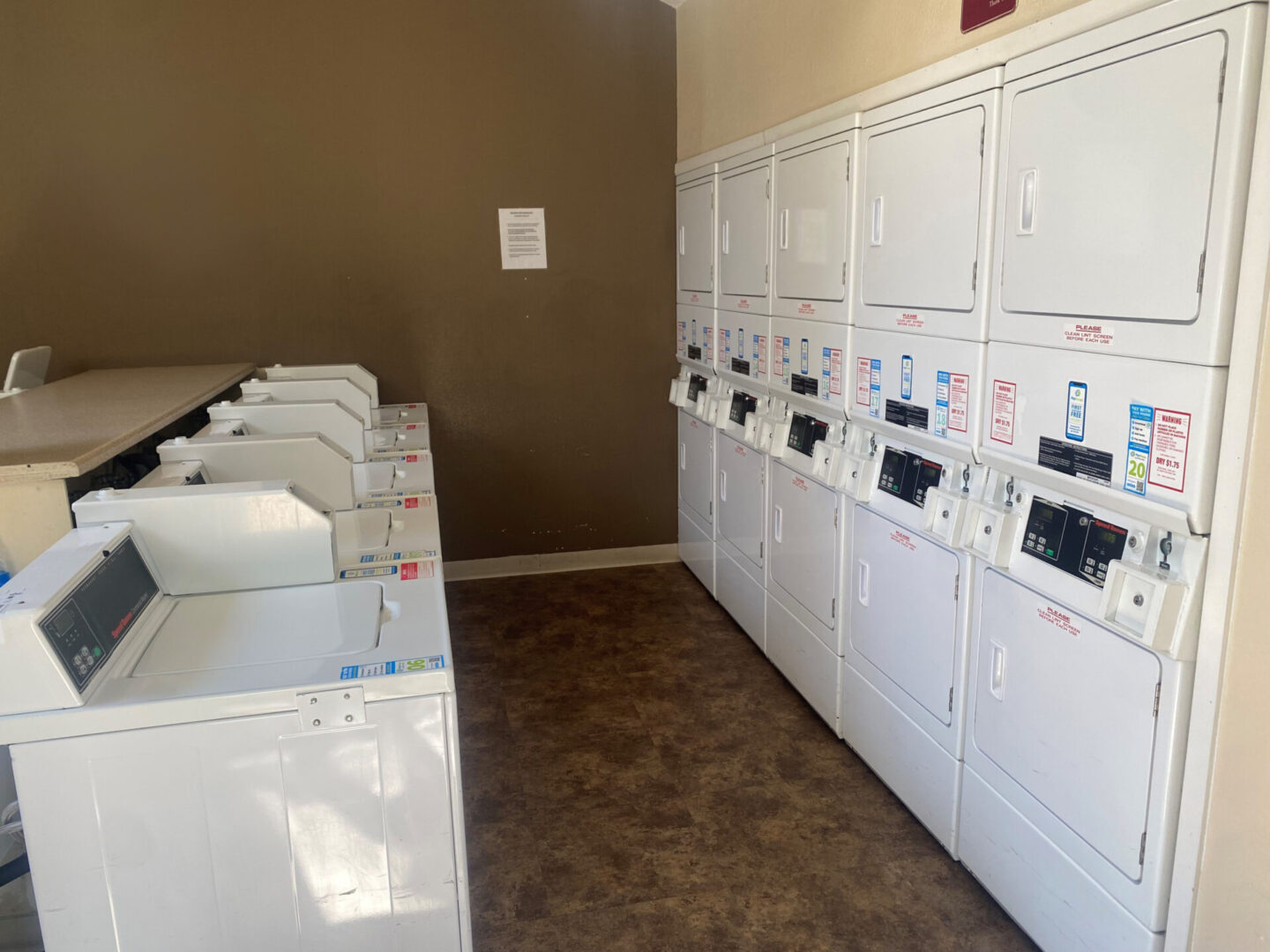 A room filled with lots of white laundry machines.