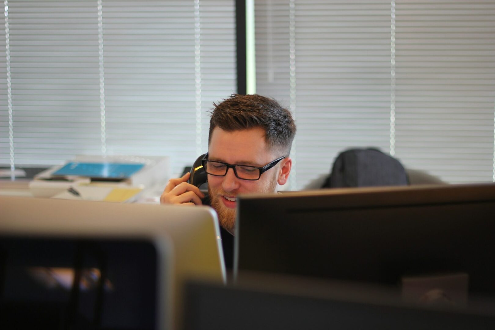 A man sitting at his desk on the phone.